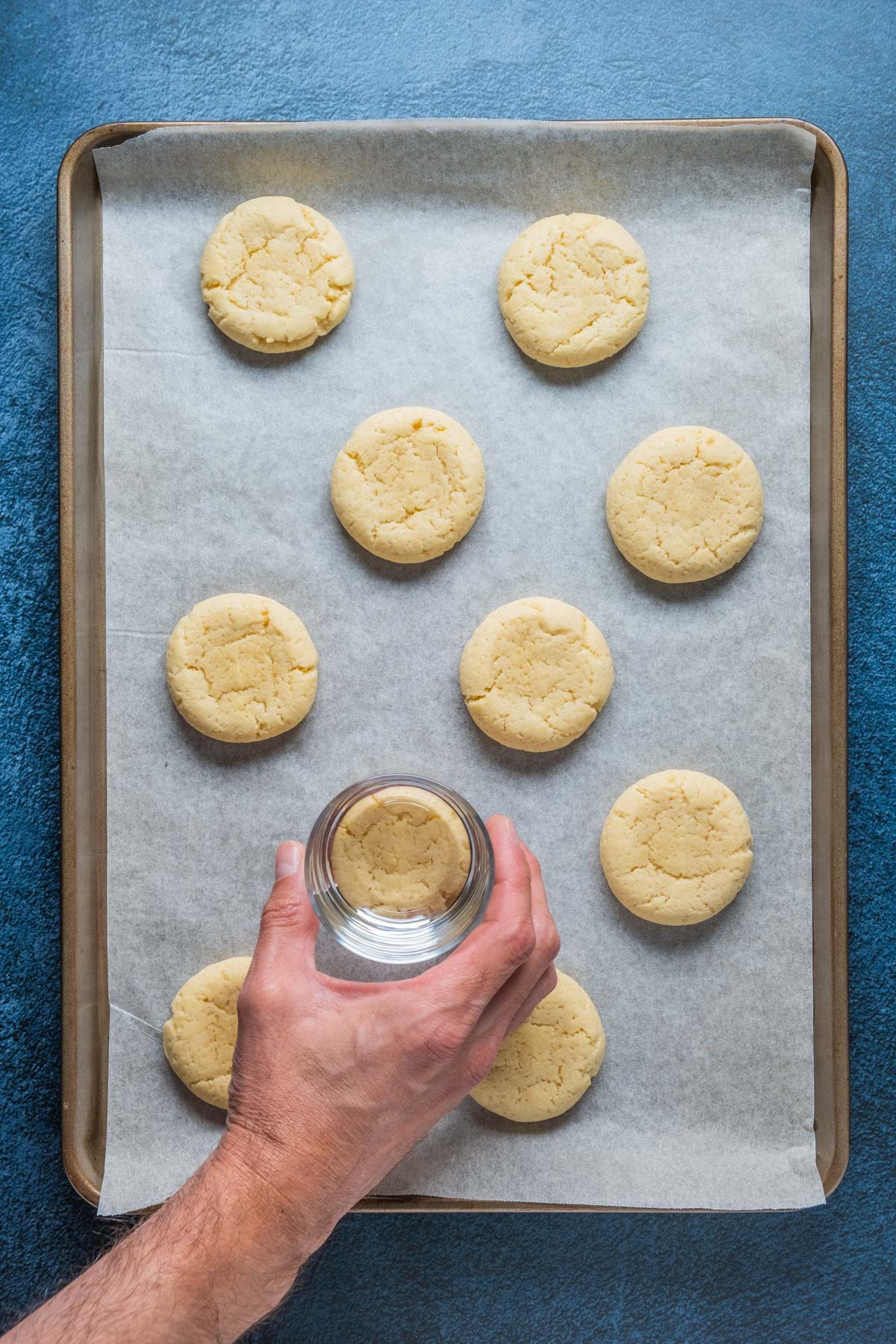 Pressing down on cookies with the base of a glass.