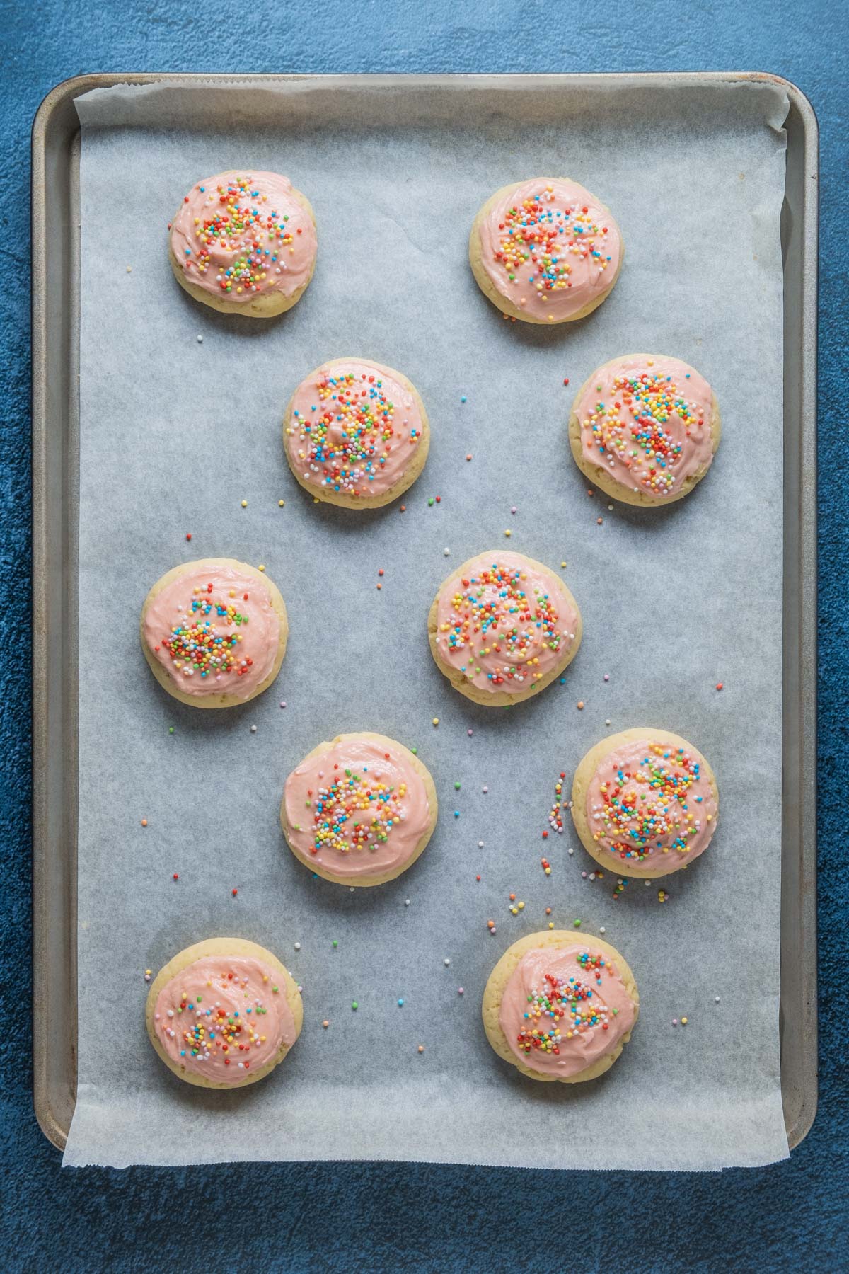 Frosted and decorated sugar cookies on a parchment lined baking sheet.