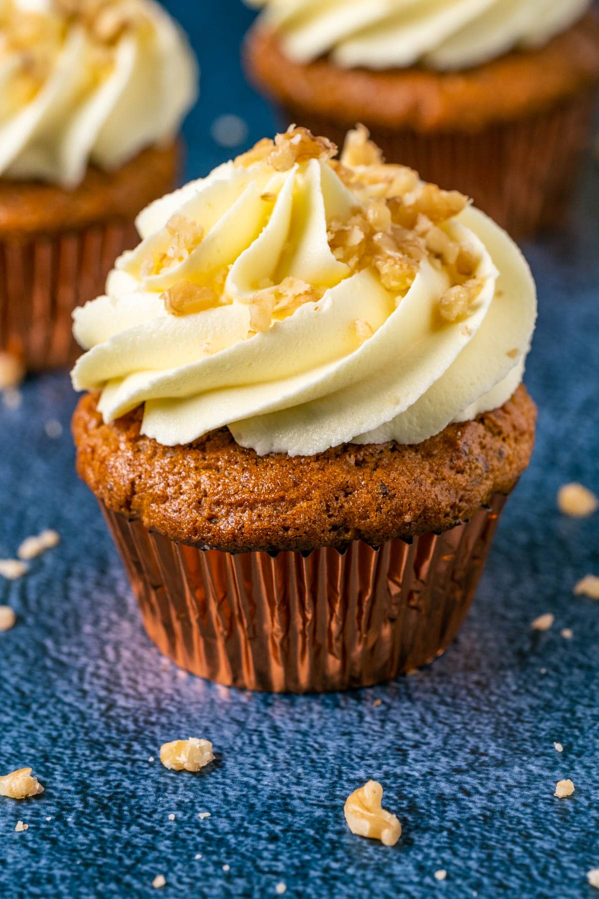 Gluten free carrot cake cupcakes topped with frosting and chopped walnuts. 