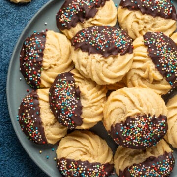 Vegan butter cookies stacked up on a plate.