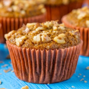 Vegan carrot muffins in orange liners and topped with chopped walnuts.