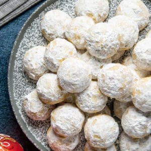 Vegan snowball cookies stacked up on a plate.