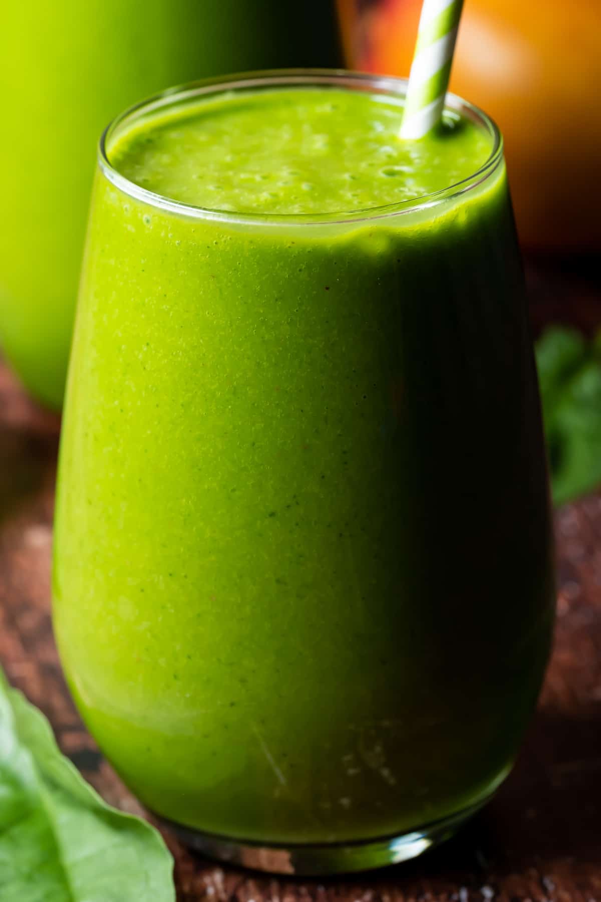 Vegan green smoothie in a glass with a straw. 