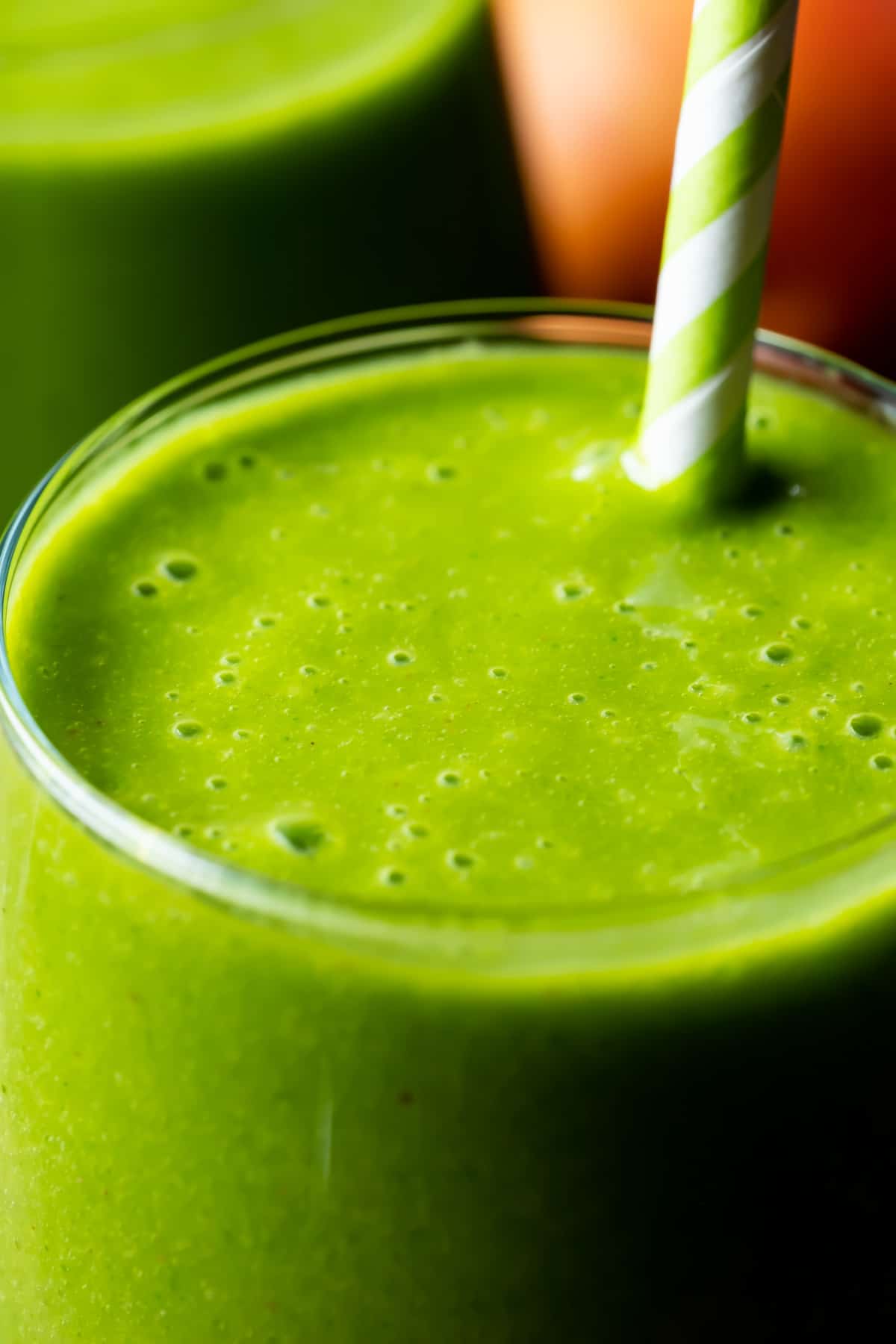Green smoothie in a glass with a straw.
