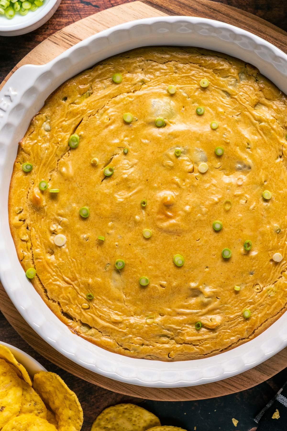 Vegan buffalo chicken dip topped with chopped green onions in a white dish.