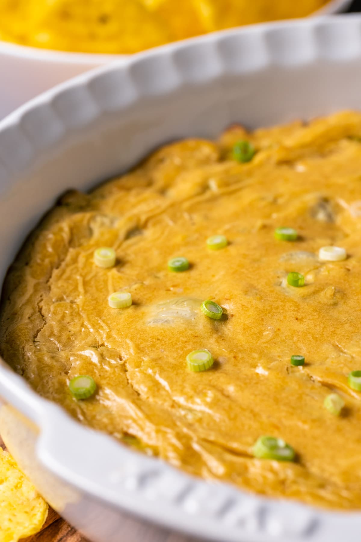 Vegan buffalo dip with green onions in a white dish. 