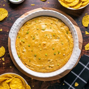 Vegan buffalo chicken dip with green onions in a white dish.