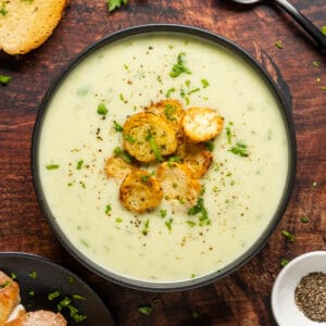 Vegan celery soup with croutons in a black bowl.