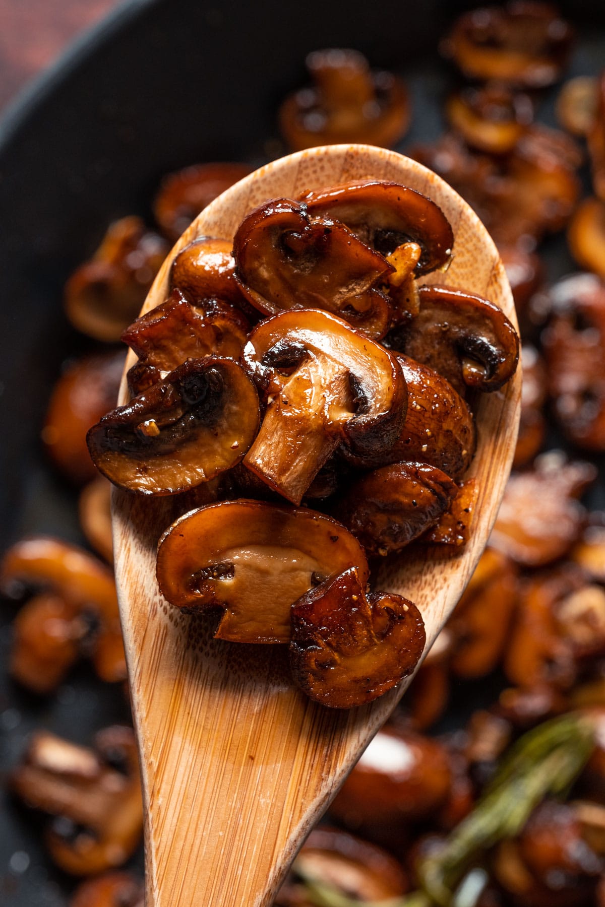 Vegan garlic mushrooms on a wooden spoon.