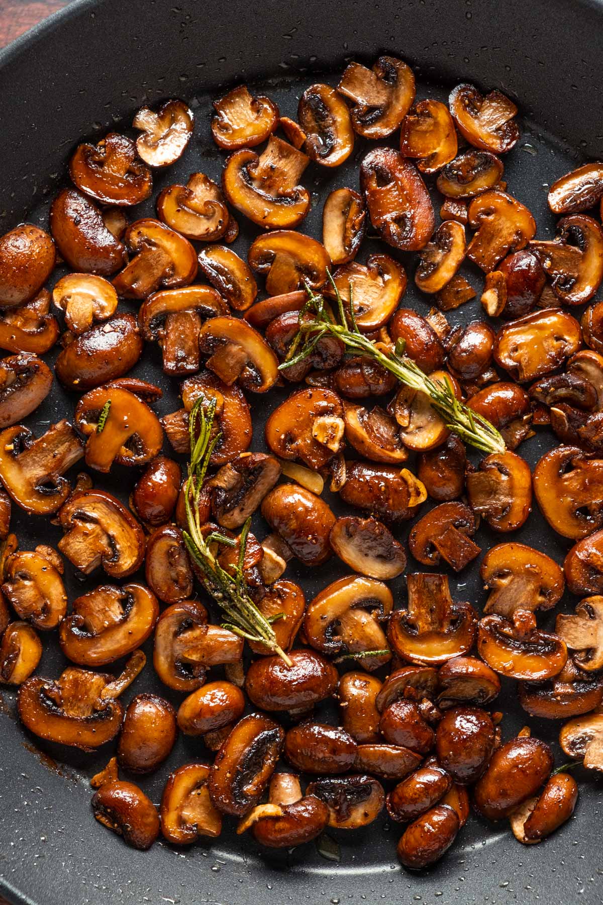 Vegan garlic mushrooms in a skillet with rosemary. 