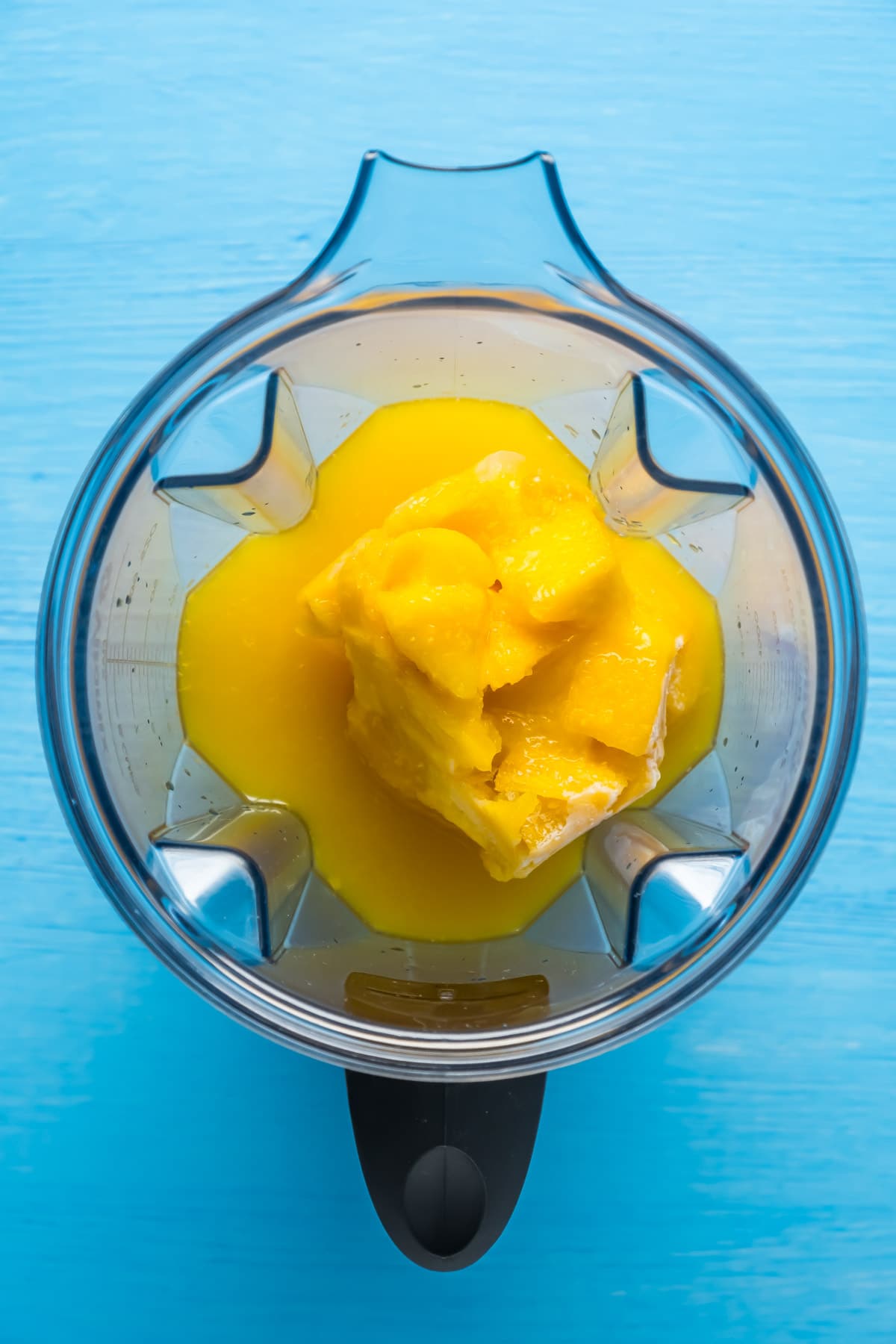 Ingredients for mango orange smoothie added to blender.