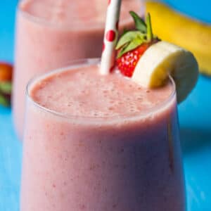 Strawberry banana smoothie in glasses with straws.