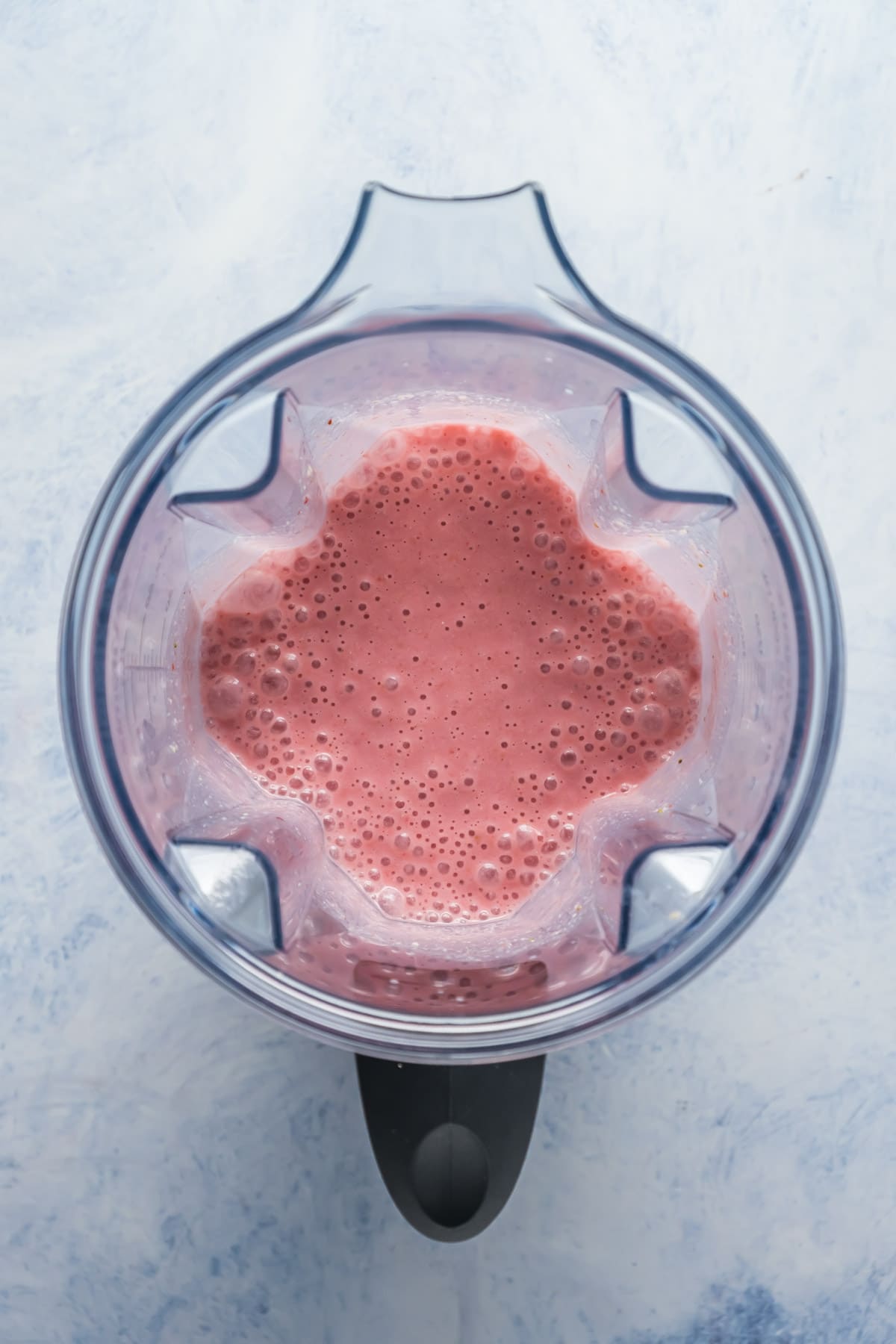 Blended strawberry smoothie in blender jug.