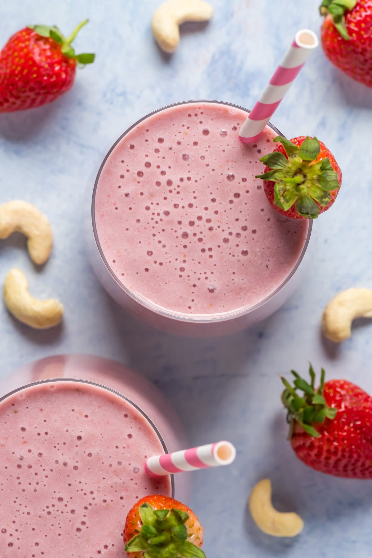 Strawberry smoothies in glasses with striped straws. 