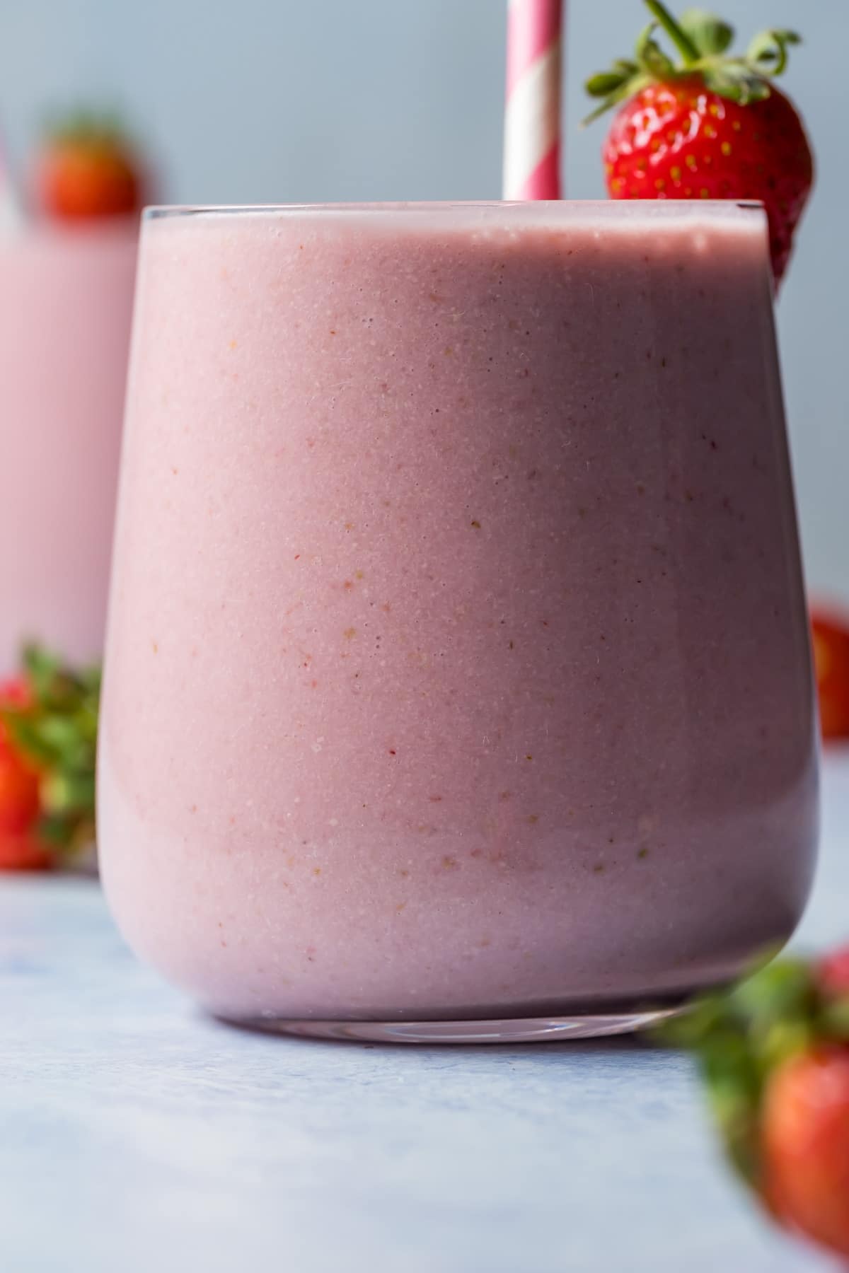 Strawberry smoothies in glasses with striped straws.