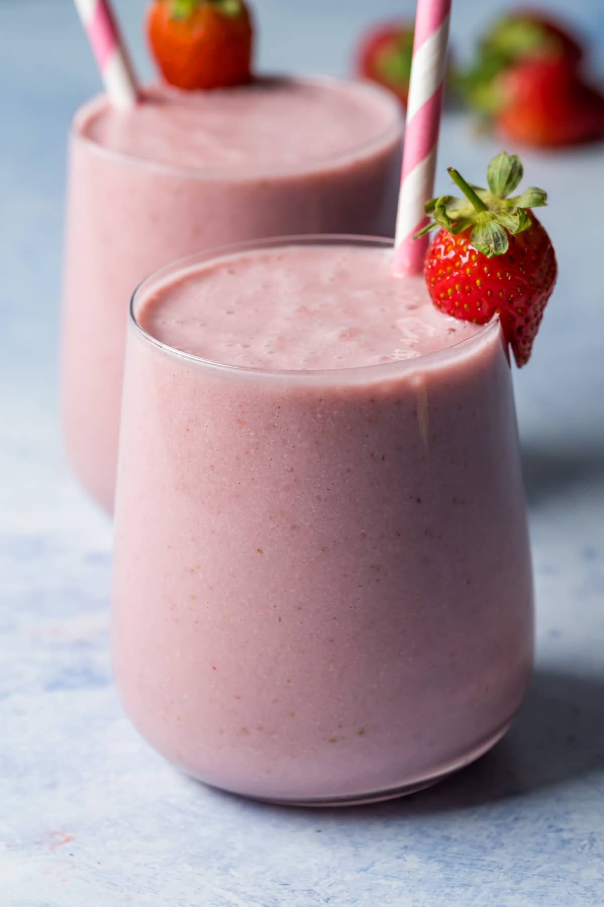 Strawberry smoothies in glasses with striped straws.