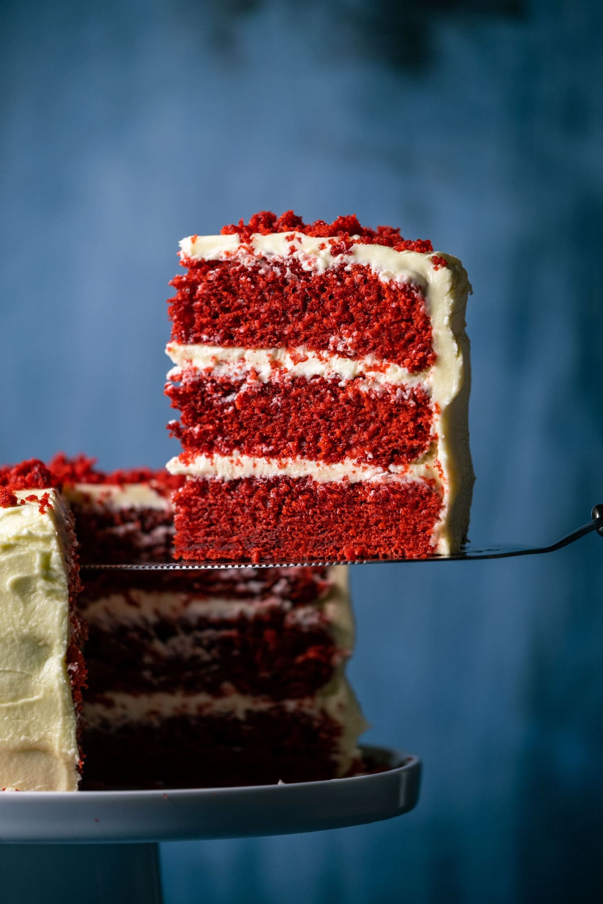 Slice of vegan red velvet cake on a cake lifter.