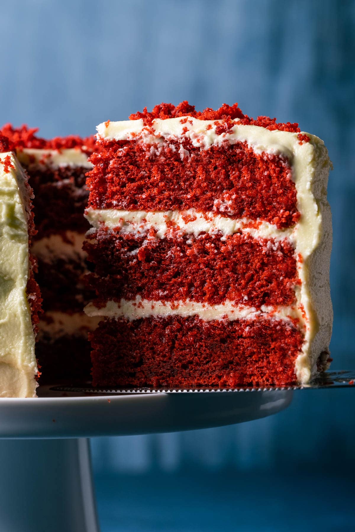 Slice of vegan red velvet cake on a cake lifter.
