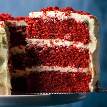 Sliced vegan red velvet cake on a white cake stand.