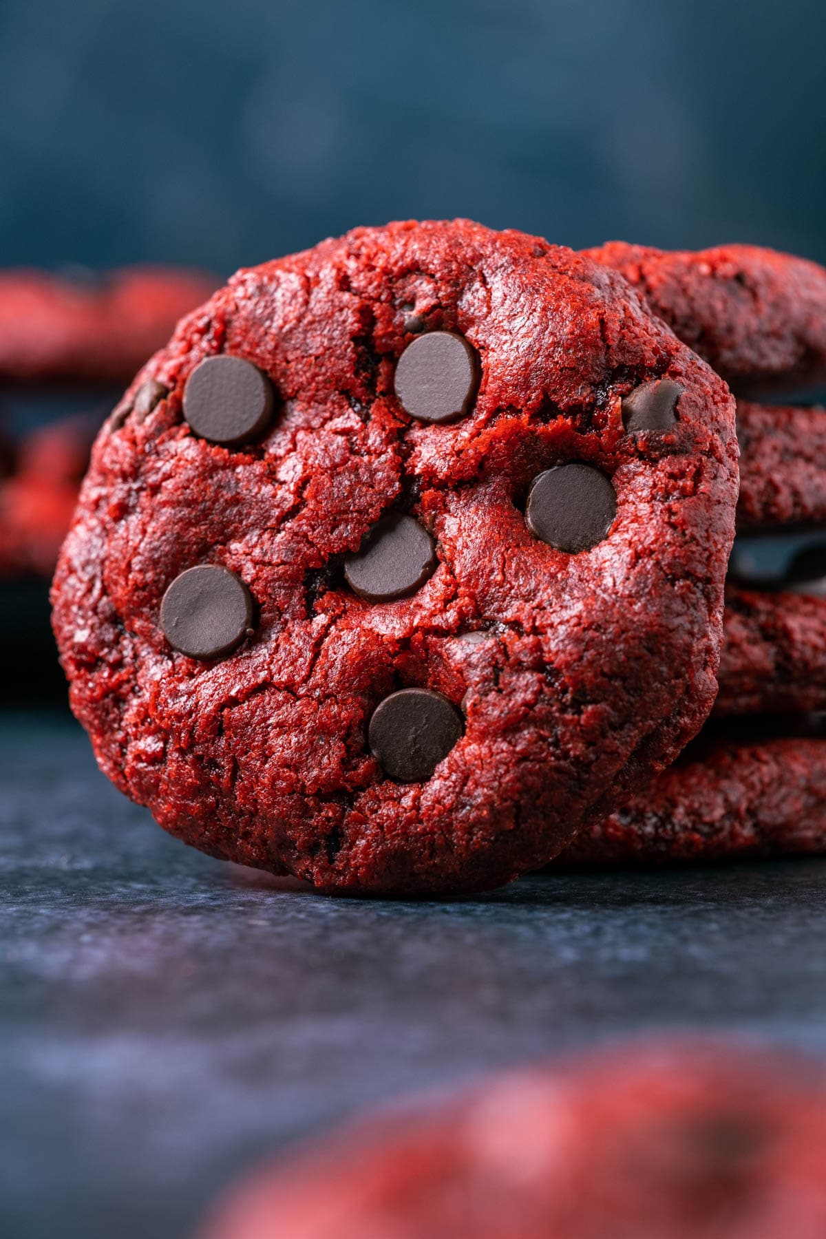 Vegan red velvet cookie leaning against a stack of cookies.