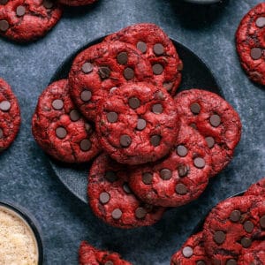 Red velvet cookies stacked up on a black plate.