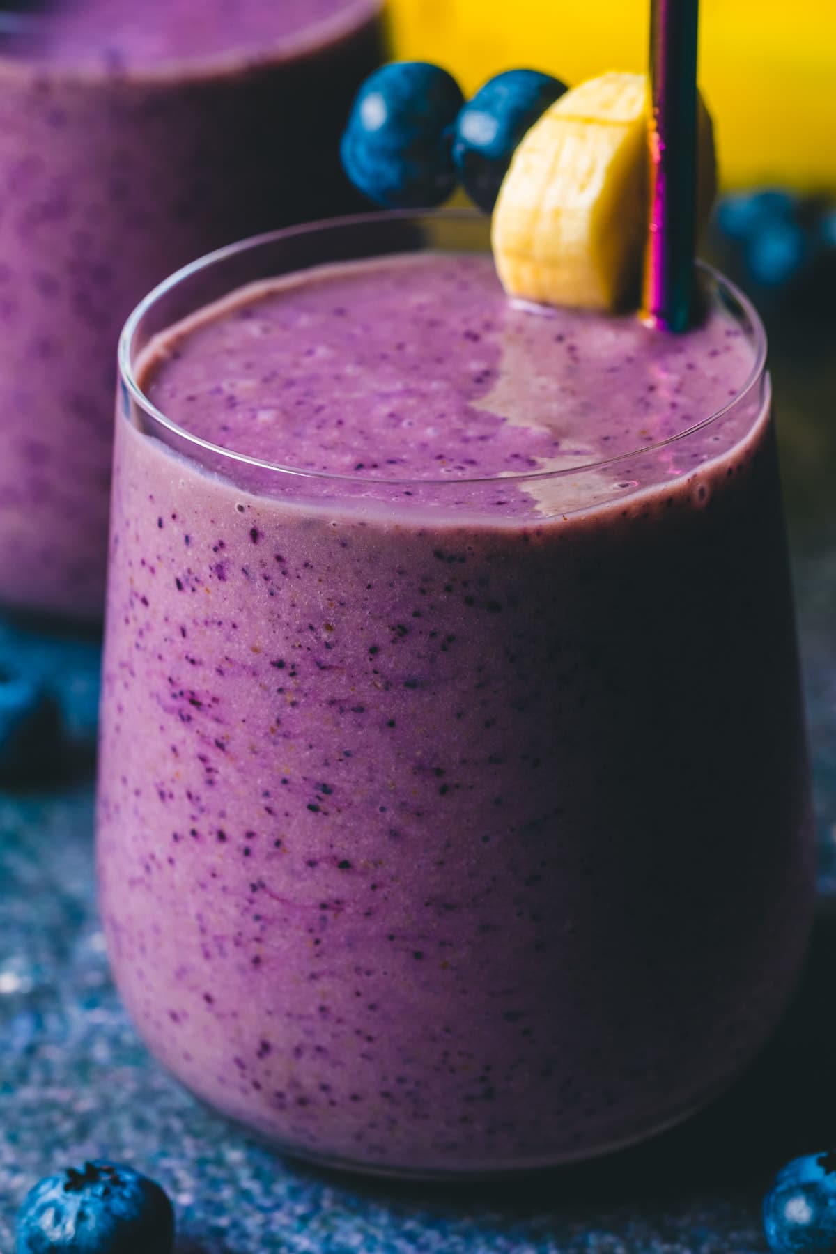 Blueberry banana smoothie in a glass with a straw.