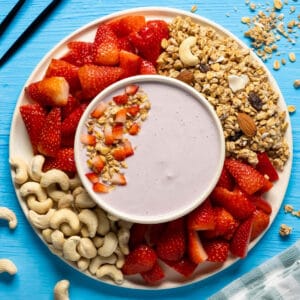 Vegan yogurt in a bowl with granola and sliced strawberries.