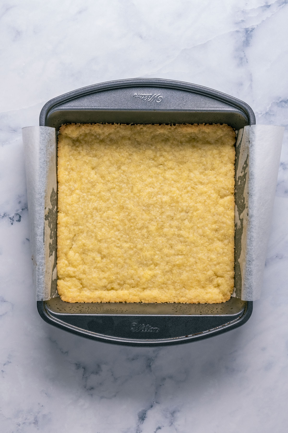 Baked vegan shortbread crust in a square dish.