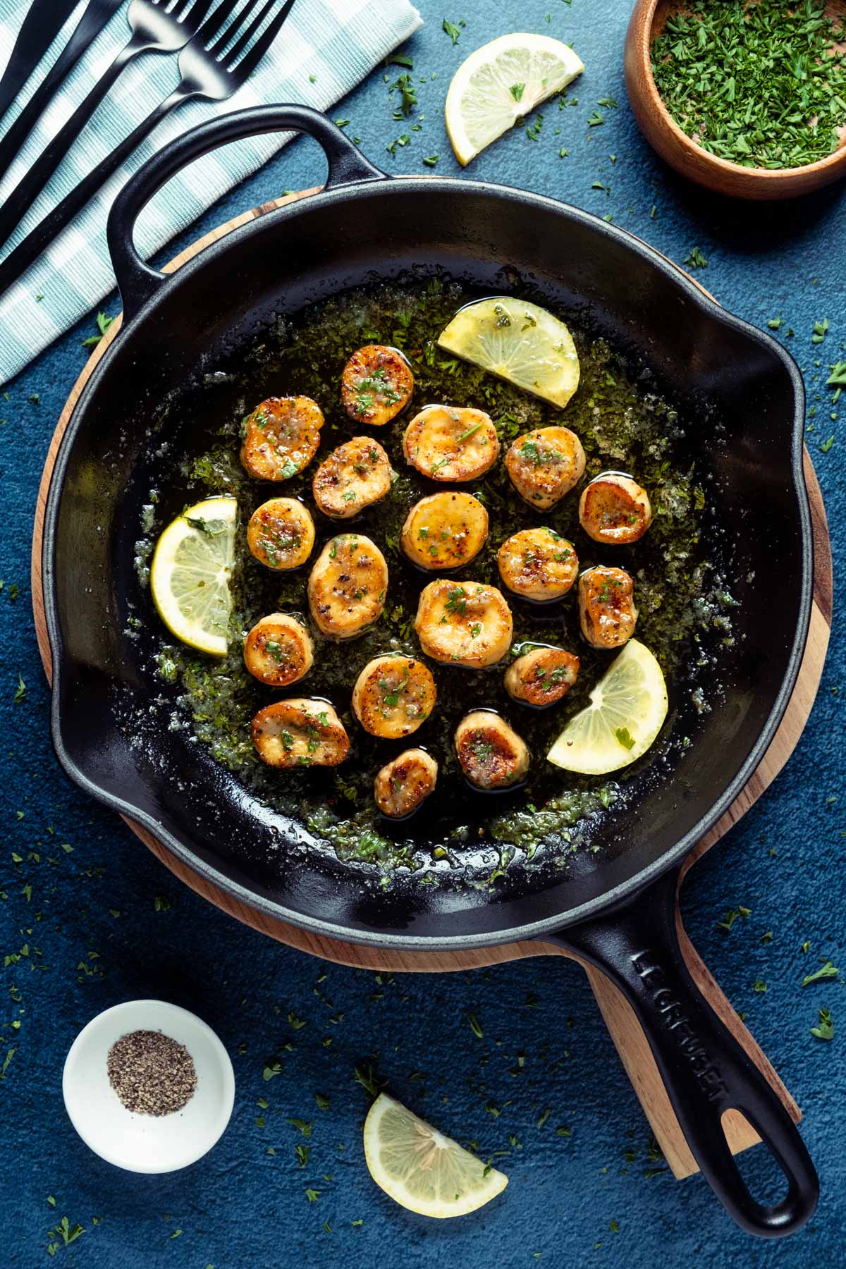 Vegan scallops in a frying pan with lemon slices and parsley.
