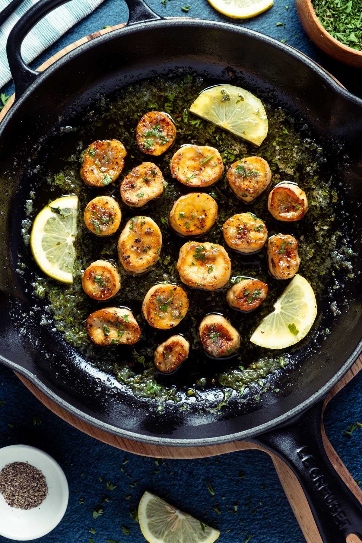Vegan scallops in a frying pan with lemon slices and parsley. 