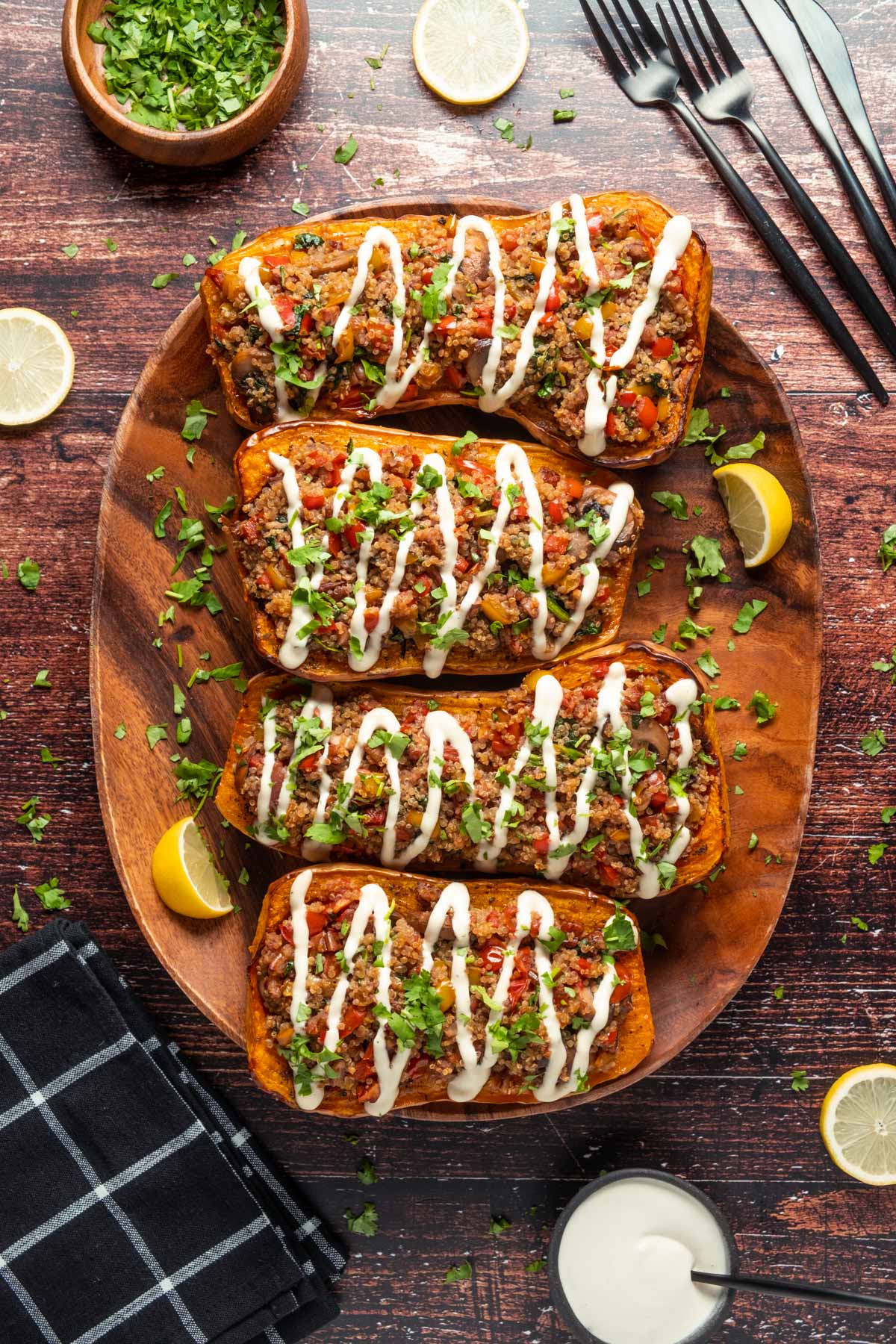 Stuffed butternut squash drizzled with cashew cream on a wooden serving platter.
