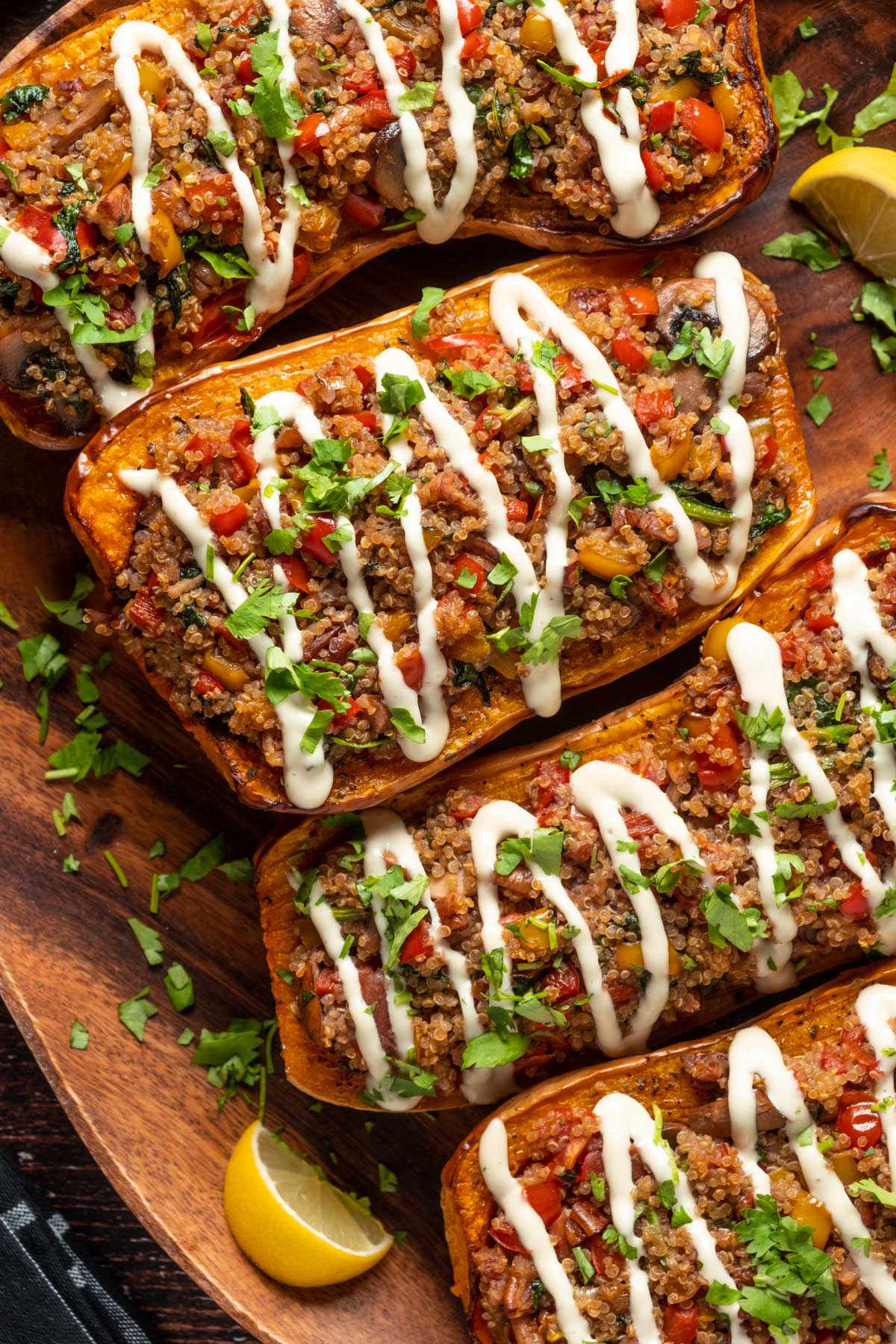 Stuffed butternut squash drizzled with cashew cream and sprinkled with fresh chopped cilantro on a serving platter.