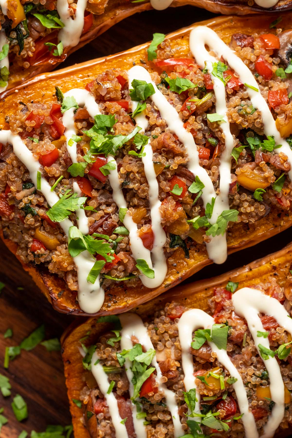 Stuffed butternut squash drizzled with cashew cream and sprinkled with fresh chopped cilantro on a serving platter.