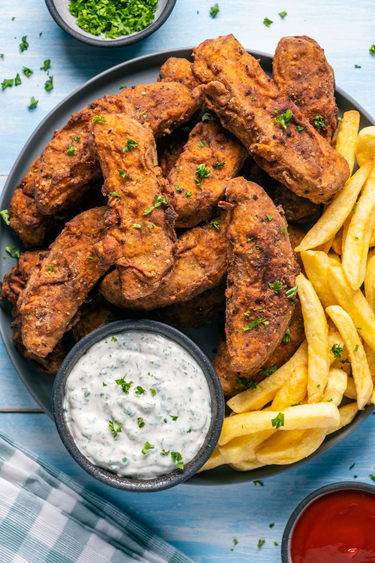 Vegan fried chicken pieces on a plate with vegan ranch dressing and chips. 