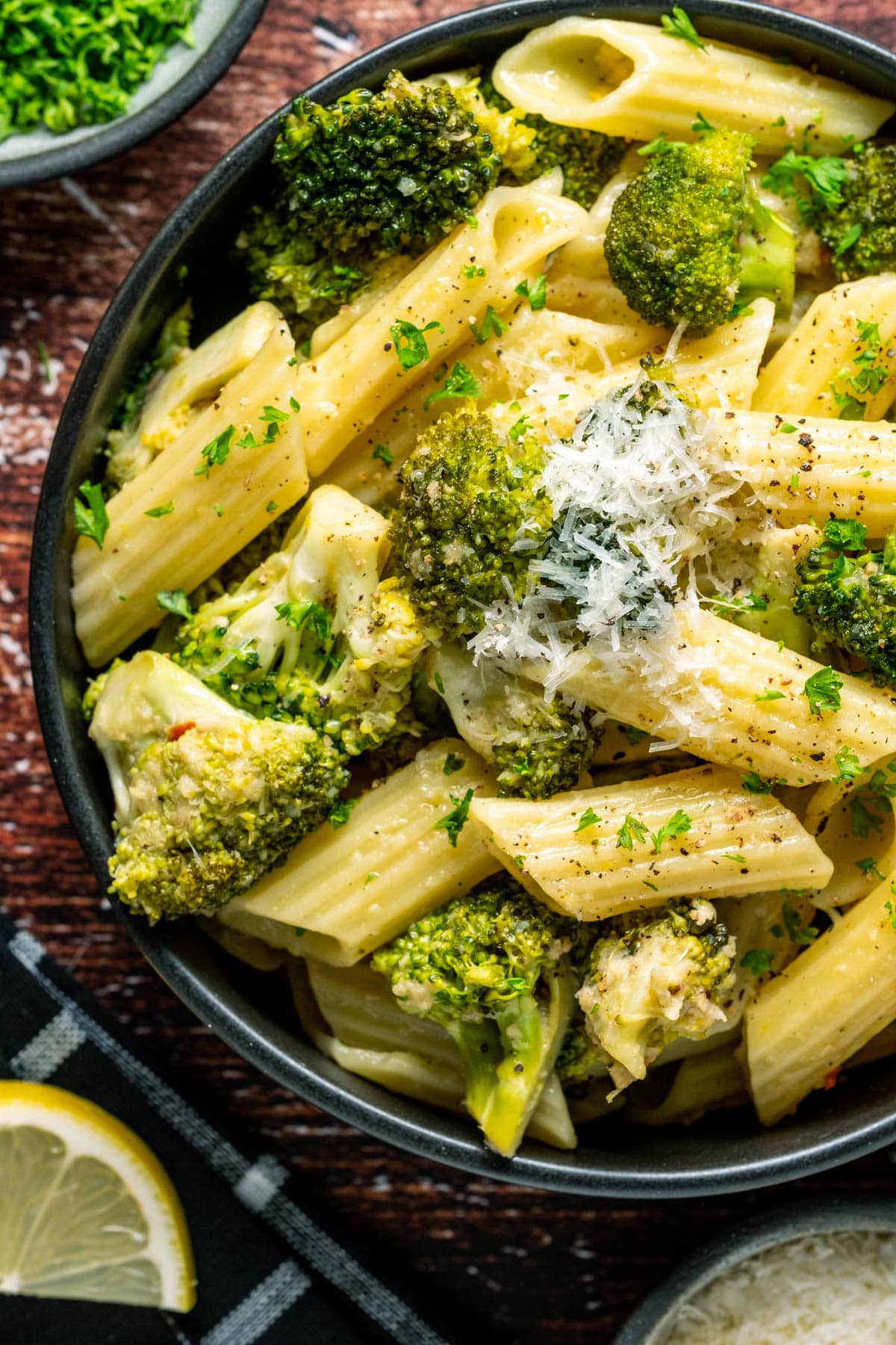 Vegan broccoli pasta topped with vegan parmesan in a black bowl. 