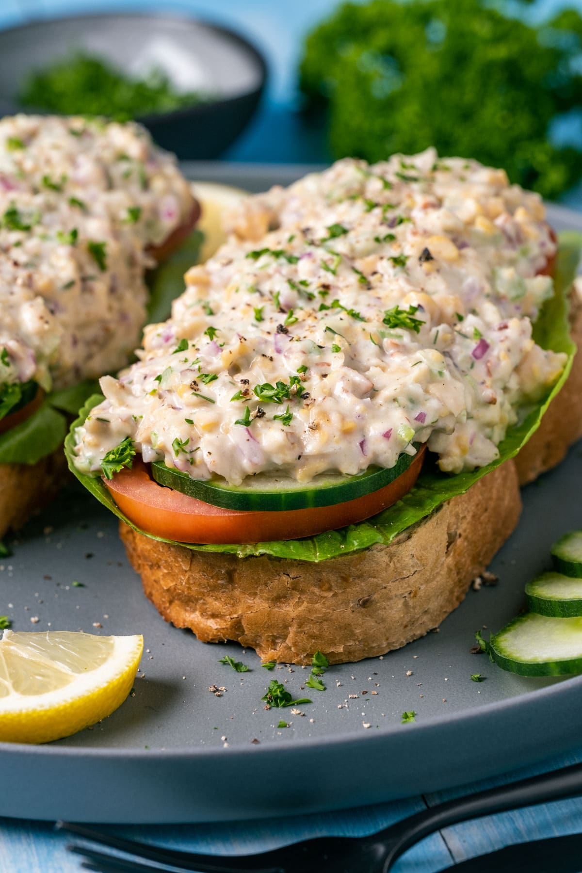 Open faced sandwiches topped with vegan chicken salad on a gray plate.