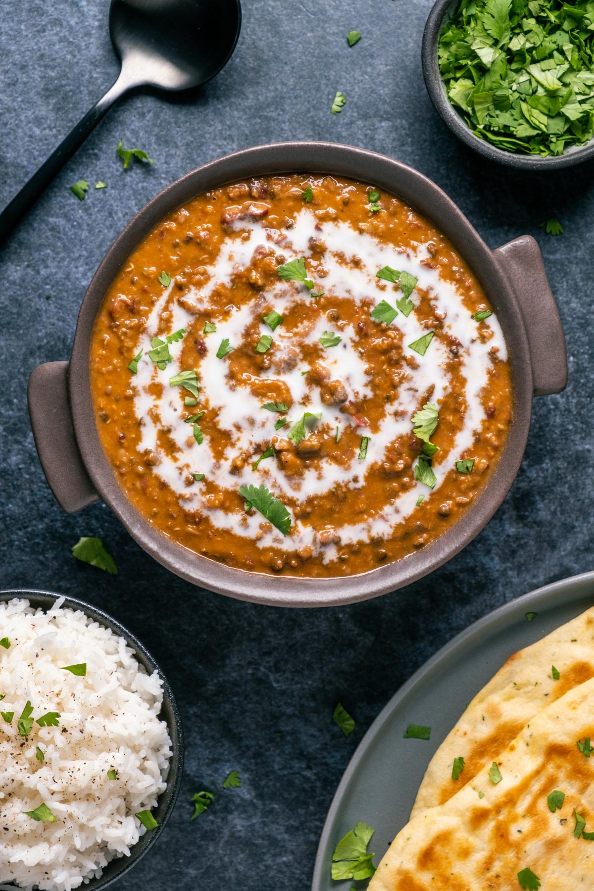 Vegan dal makhani topped with a drizzle of coconut cream and fresh chopped cilantro in a brown bowl.