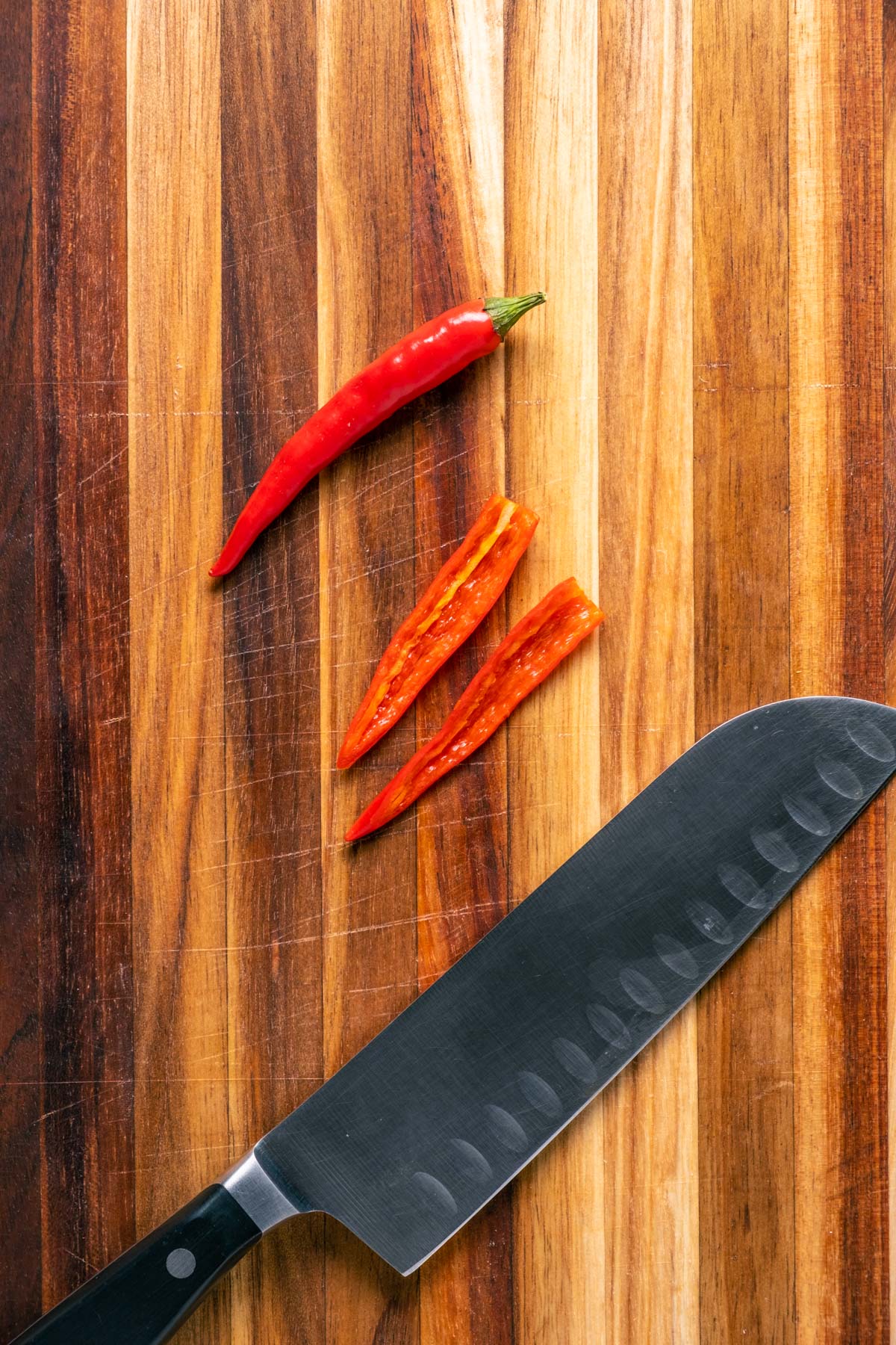 Slicing chili on a wooden cutting board.