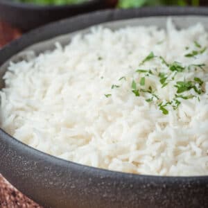Basmati rice with fresh parsley in a black bowl.