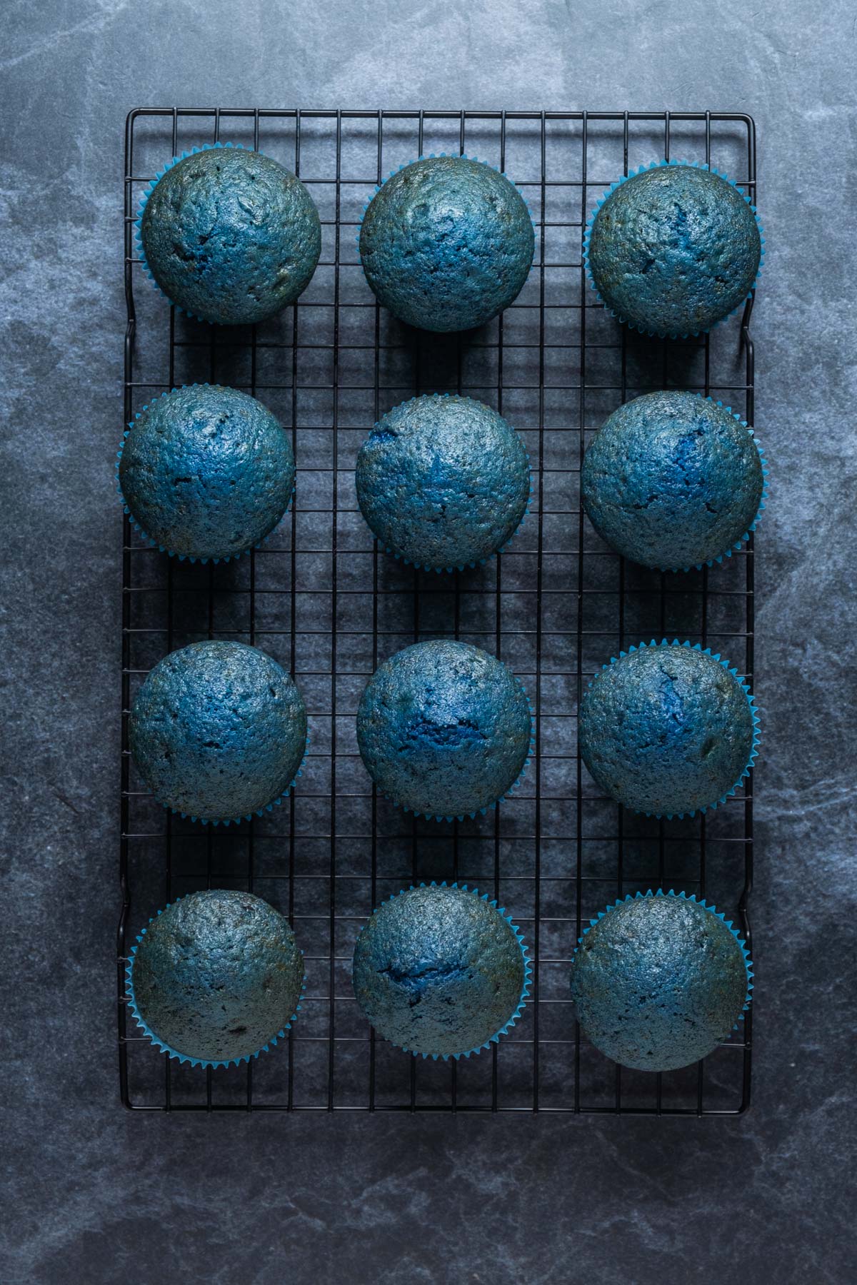 Vegan blue velvet cupcakes cooling on a wire cooling rack.