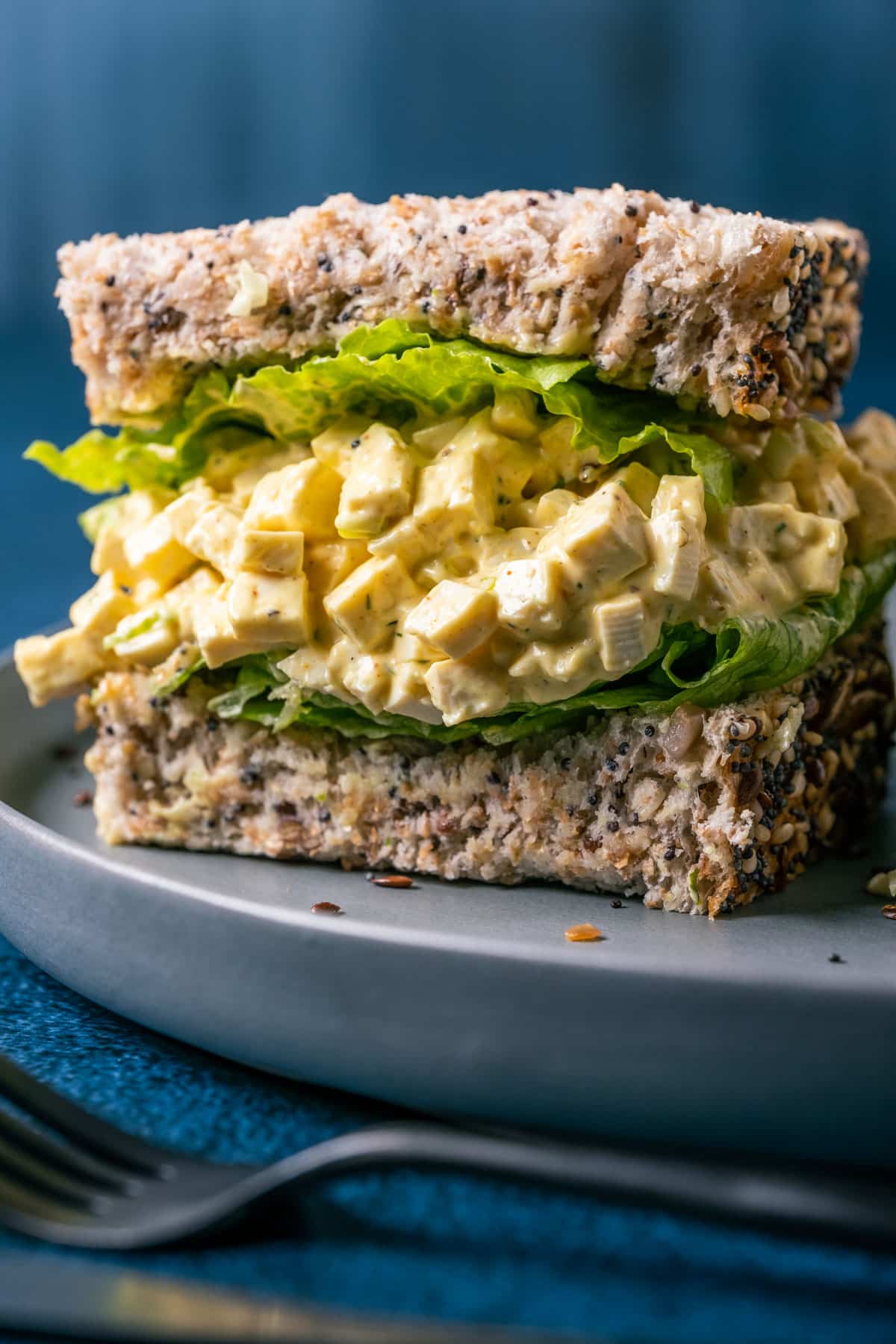 Vegan egg salad sandwich cut in half on a gray plate.