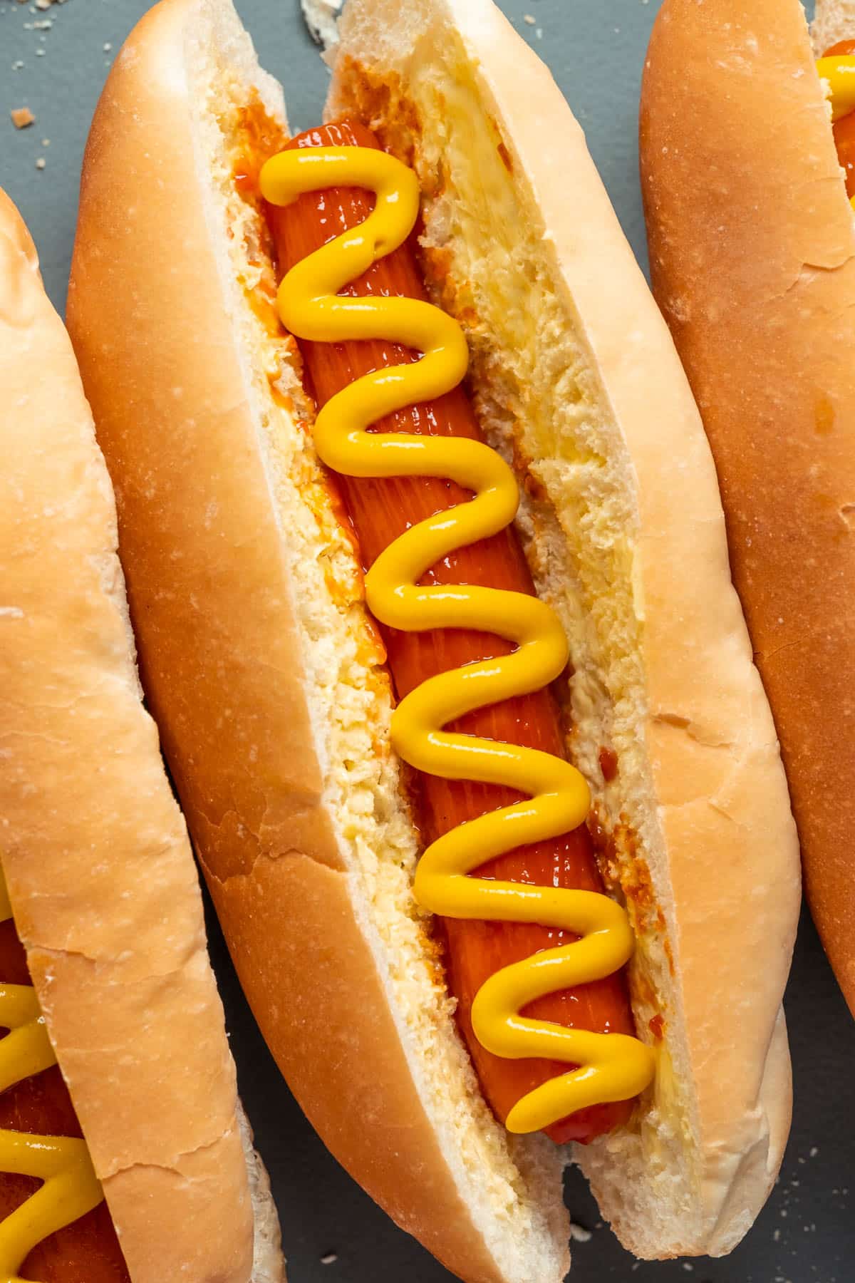 Carrot dogs with mustard on a gray plate.