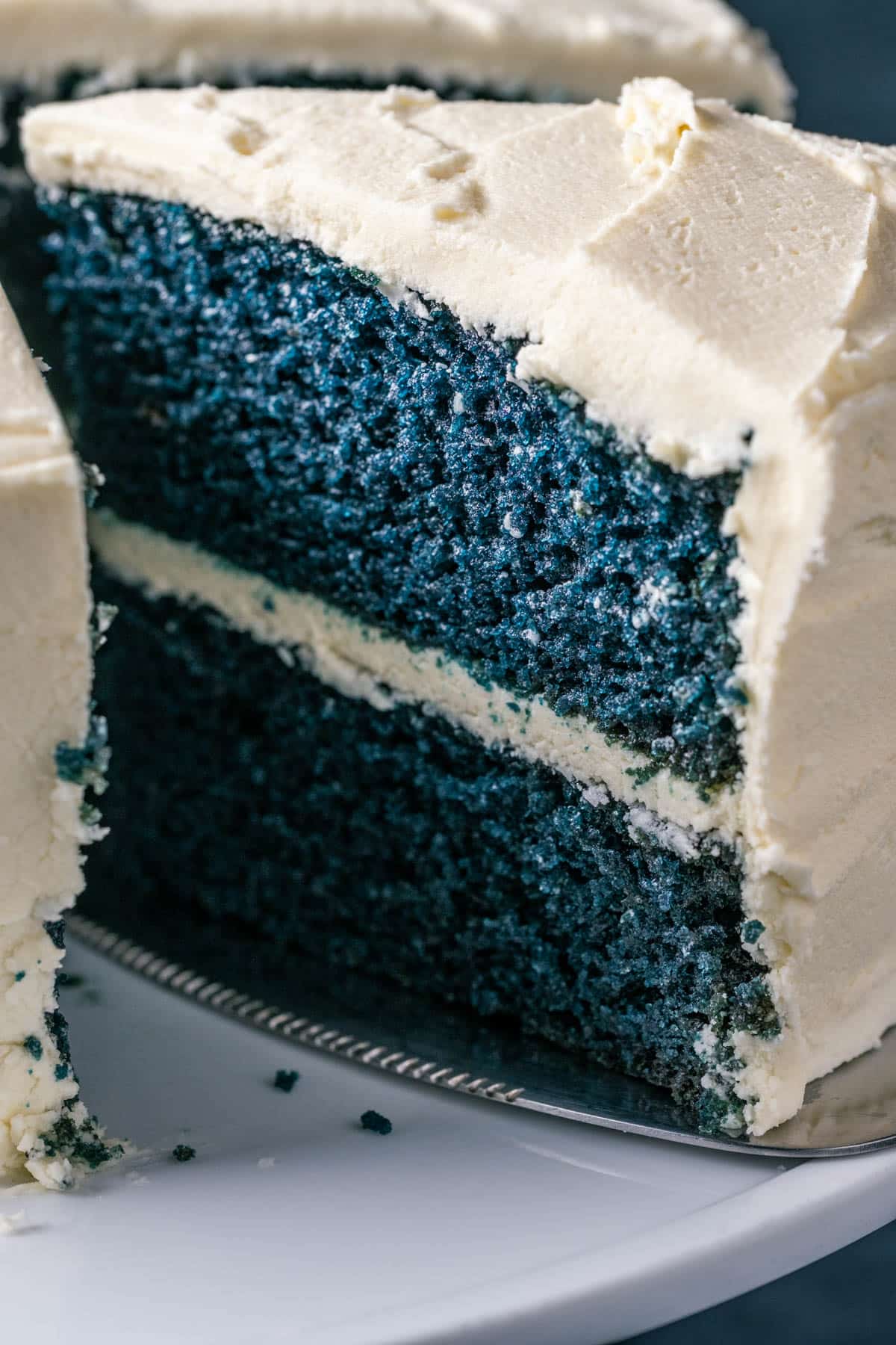 Sliced blue velvet cake on a white cake stand.