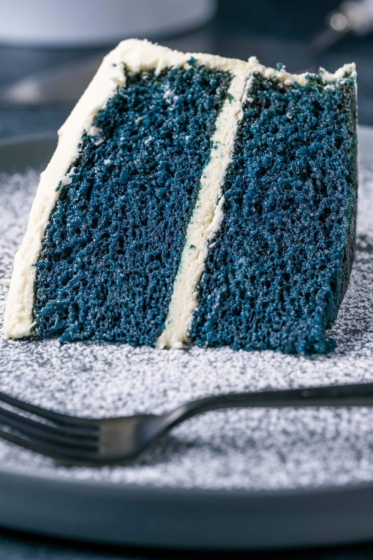 Slice of blue velvet cake on a plate with a cake fork.