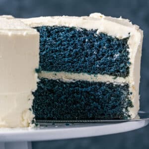 Sliced vegan blue velvet cake on a white cake stand.