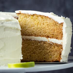 Sliced vegan key lime cake on a white cake stand.