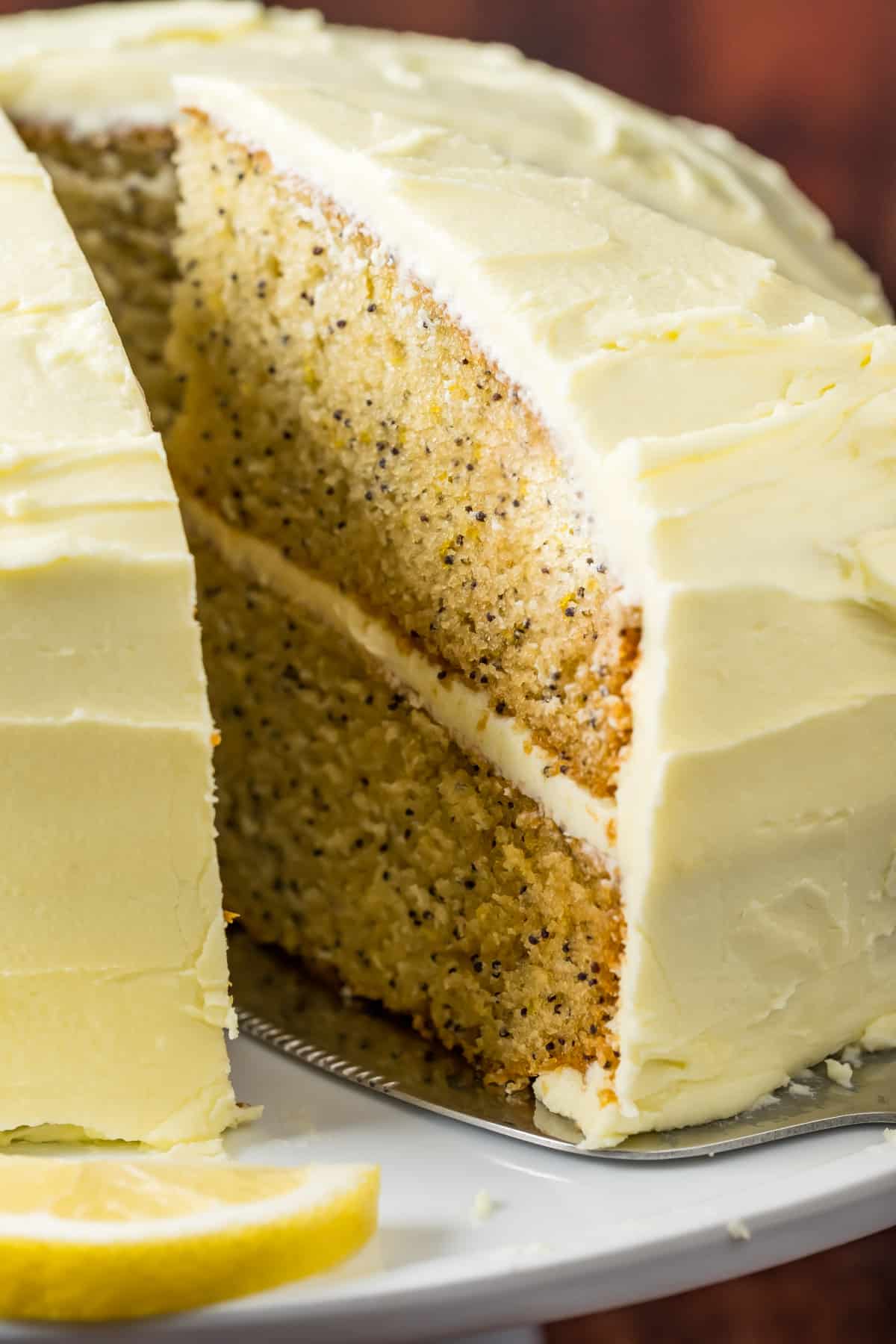Sliced vegan lemon poppy seed cake on a white cake stand. 