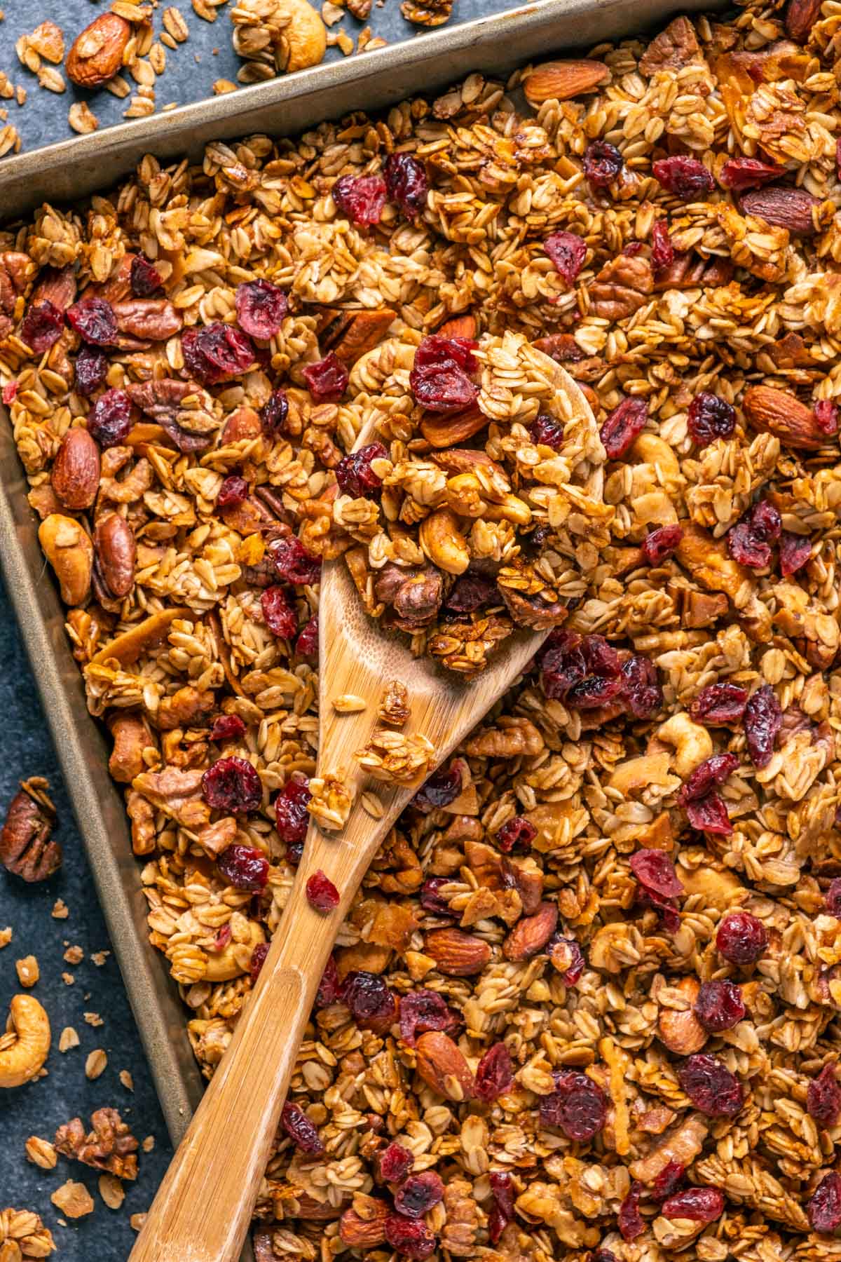 Vegan granola on a baking sheet with a wooden spoon. 