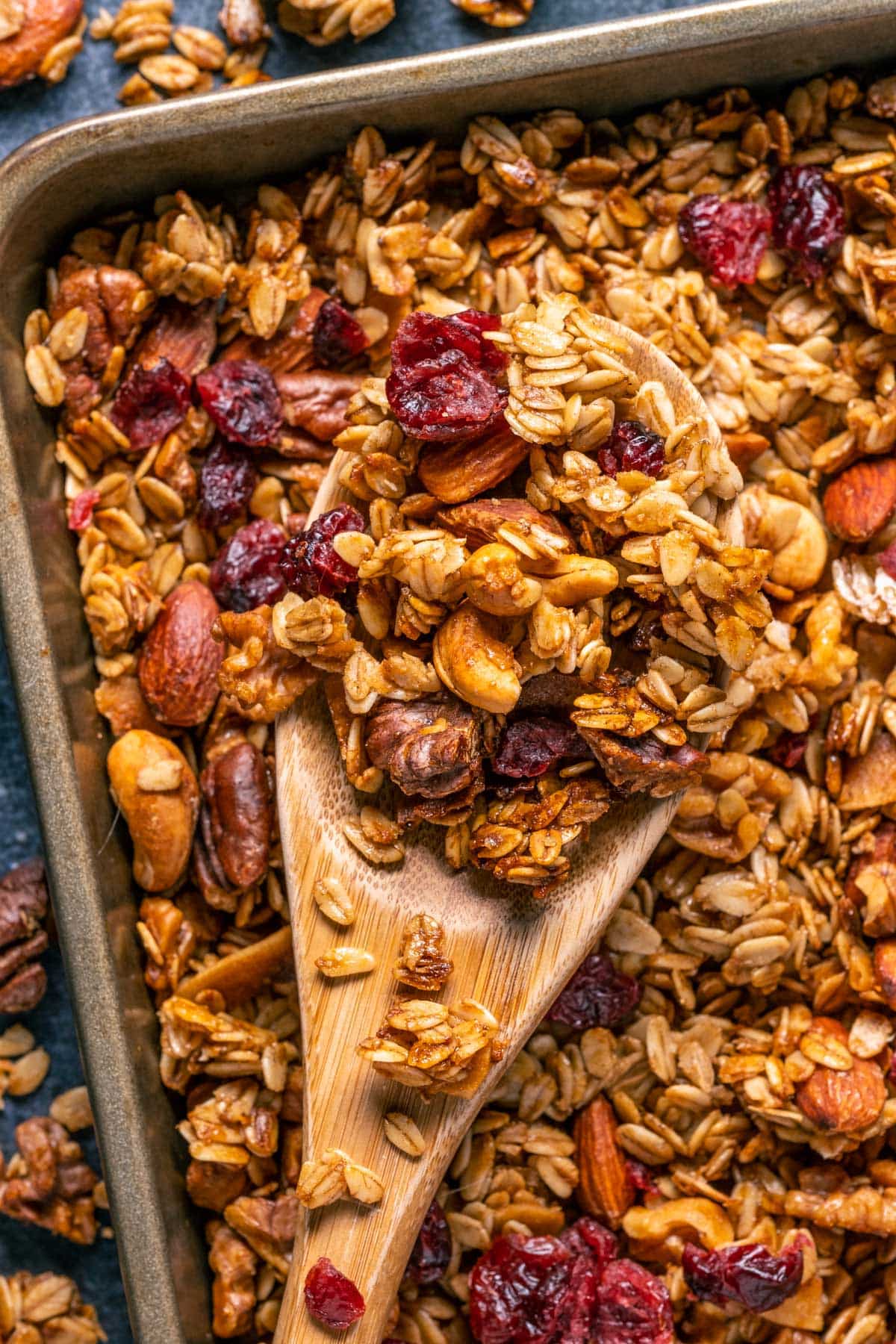 Vegan granola on a baking sheet with a wooden spoon.