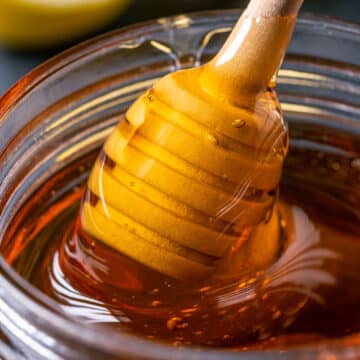 Vegan honey in a glass jar with a honey dipper.